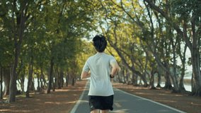 Attractive asian man jogging in the park on a background of trees with sunlight, Fitness Man Running, Training Run Workout. - Powered by Shutterstock - Get 15% off with code: PIKWIZARD15