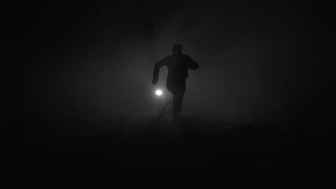 Silhouette of a man running in slow motion through the forest at winter night