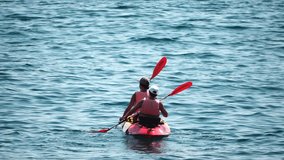 Aerial view of a family kayaking in calm blue sea. Unrecognizable woman, man and childrens. Kayak on turquoise sea water during warm day at sea. Summer holiday vacation and travel concept