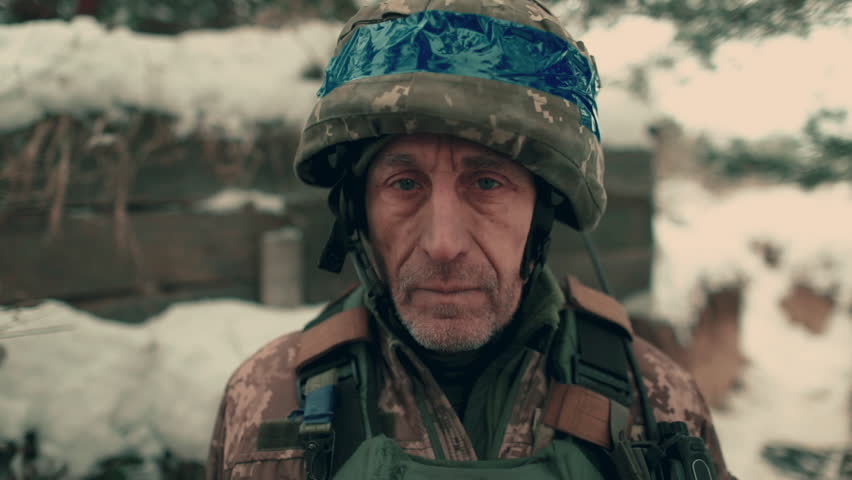 Close-up of an elderly Ukrainian soldier in military uniform and helmet. A Ukrainian soldier in a snowy trench. Royalty-Free Stock Footage #3408545911