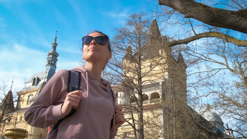 Female visiting historical castle in budapest. A cute female in sunglasses pass her free time in the park with historical vajdahunyad castle in Budapest.