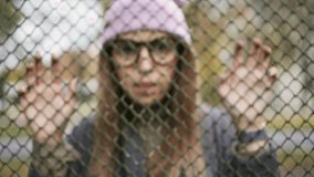 Hipster female looks at the camera, standing near the fence