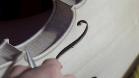 macro close up of artisan luthier maker work on new classic handmade raw violin smooth edge in waist and purfling rasp in workbench of workshop in Cremona Italy 4k video