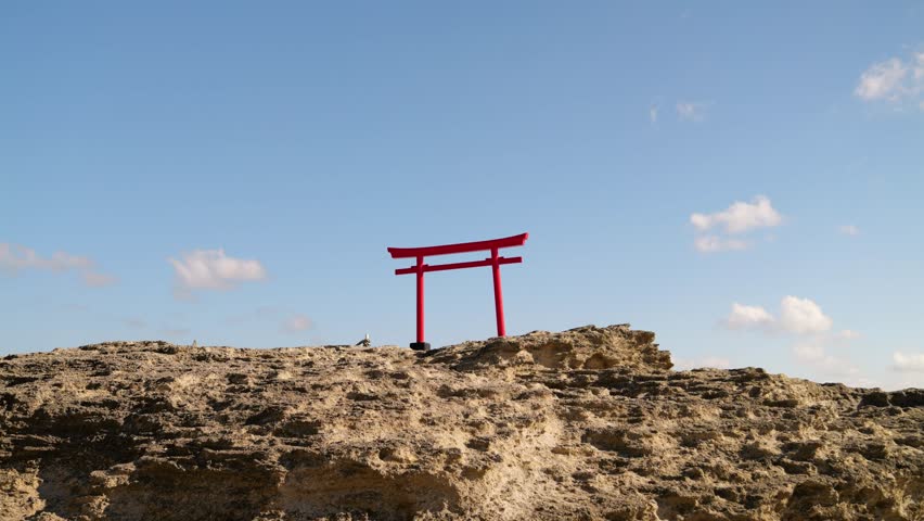 Minimalist view of Japanese red Gate on top of rocks against blue sky