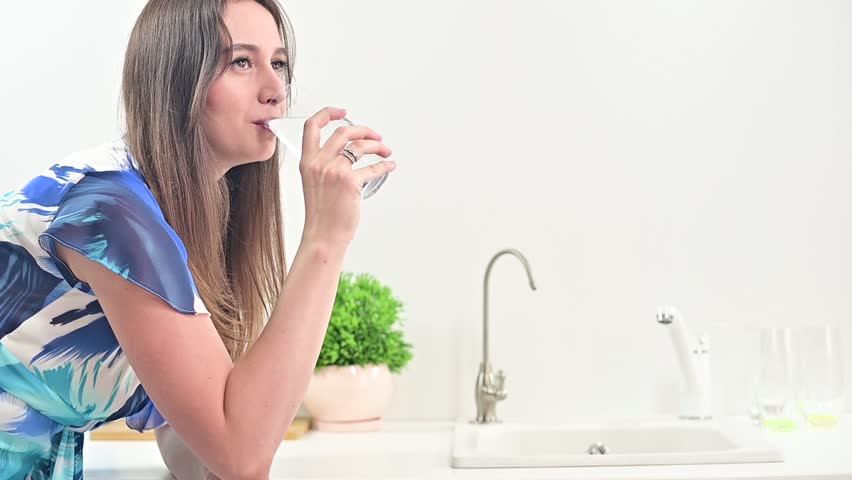 Positive Woman Hydrating in Modern Kitchen - Lifestyle Wellness Royalty-Free Stock Footage #3408918229