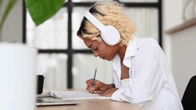E-learning,online education concept.Happy student in headphones writing down lectures,doing homeworl,listening to podcast etc - Powered by Shutterstock - Get 15% off with code: PIKWIZARD15