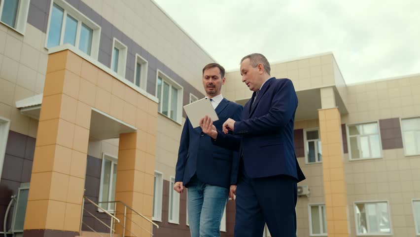 Two politicians talking on city street. Businessmen talking to each other, making successful contractual partnership agreement. Businessmen in suits work with tablet on city street, working as team. Royalty-Free Stock Footage #3408997053