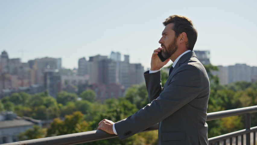 Successful manager calling on street looking at sunny city panorama close up. Elegant bearded businessman talking smartphone standing urban area. Confident man ceo discussing work by cellphone outside - Powered by Shutterstock - Get 15% off with code: PIKWIZARD15