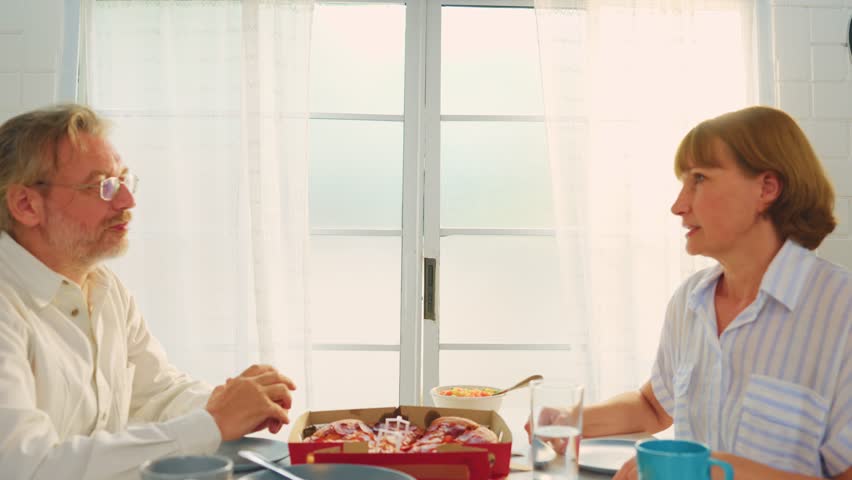 Caucasian lovely family having dinner, enjoying evening party in house. Attractive senior elderly grandparent and young daughter eating foods celebrate weekend reunion together at dining table at home
