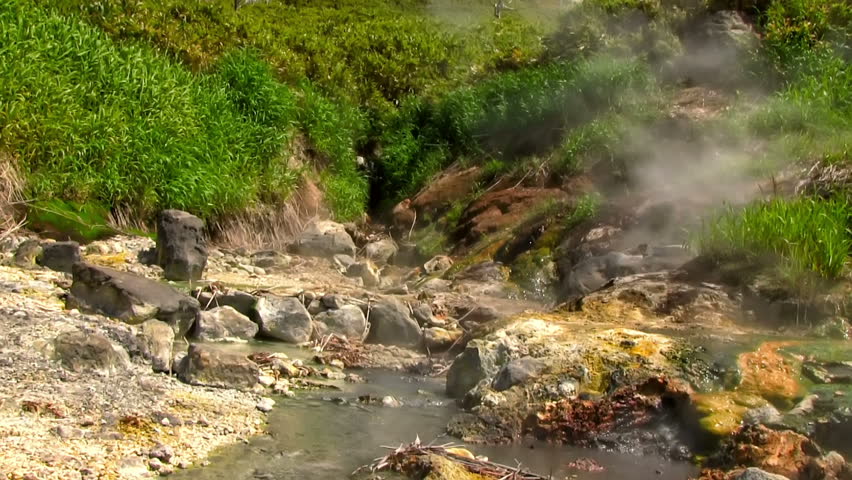 Hot drops of water slowly fall in the stream of the geothermal river on the slope of the volcano. Kuril Islands, Itutrup Island, Baranskiy Volcano. Slowmotion 240 FPS