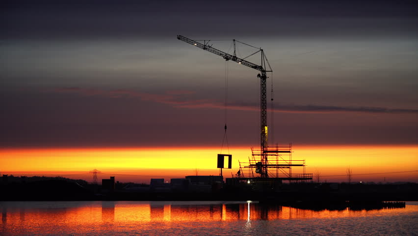 Construction of a new home with a crane during a very colorful dawn in Meerstad, Groningen.
