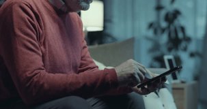 Senior man sitting on the couch at home with his android AI robot, he is using his smartphone and the robot is looking at him - Powered by Shutterstock - Get 15% off with code: PIKWIZARD15