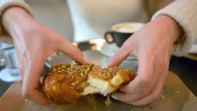 Woman breaking a french croissant with pistachio cream at a coffee shop