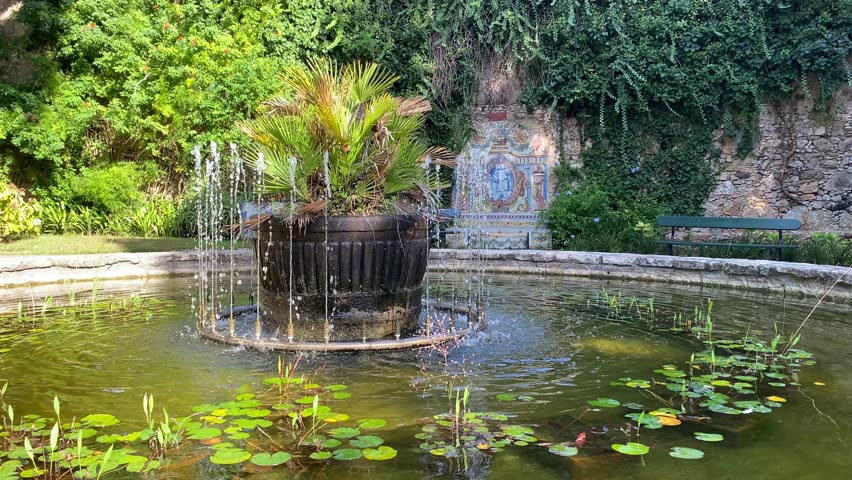 Water flows in a beautiful historical fountain in a green park