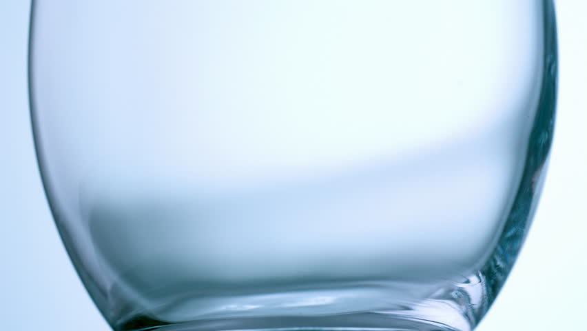 High speed shot close up of clear mineral water pouring into drinking glass