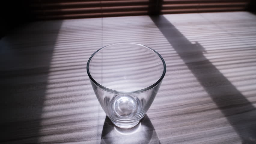 slow motion of pouring water from a plastic bottle into a glass on wooden table near the window with sunlight streaming through, Tilt up and Tracking Shot Royalty-Free Stock Footage #3409450787