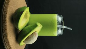 Rotating display of avocado juice on black background. Vertical footage