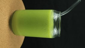 Rotating display of avocado juice on black background. Vertical footage