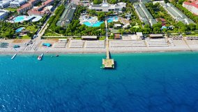 Aerial 4K drone wide top down video of a wooden pier near hotel resort in the city of Kiriş - Kemer (Antalya, Turkey). Filmed in a vibrant summer time. Mediterranean sea.