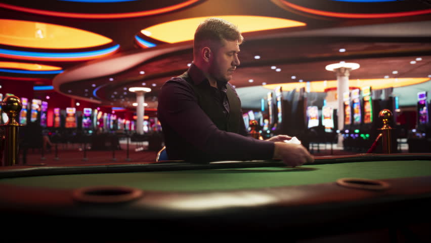 Caucasian Male Poker Dealer Is Dealing Playing Cards In Luxurious Casino. Experienced Croupier Setting Up New Game For Professional High Stakes Gamblers To Make Bets, Bluff, And Win Big Money.