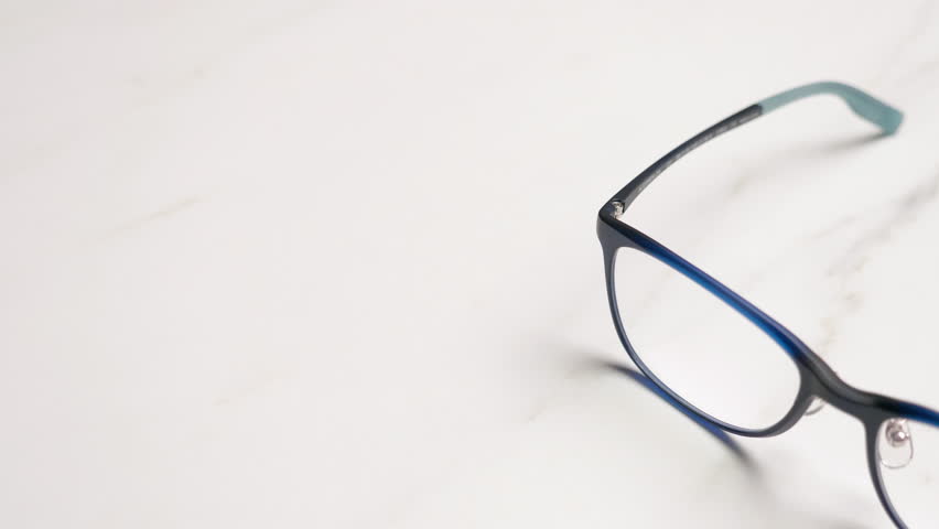 Panning on a close-up of a pair of eyeglasses placed on top of a table. Royalty-Free Stock Footage #3409510913