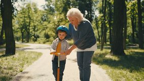 Active grandmother helping little grandson to ride scooter, family time in park - Powered by Shutterstock - Get 15% off with code: PIKWIZARD15
