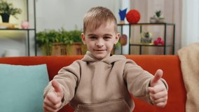 Like. Happy young Caucasian child boy looking approvingly at camera showing thumbs up like sign positive something good, positive feedback. Male little teenager kid at home in living room sits on sofa - Powered by Shutterstock - Get 15% off with code: PIKWIZARD15