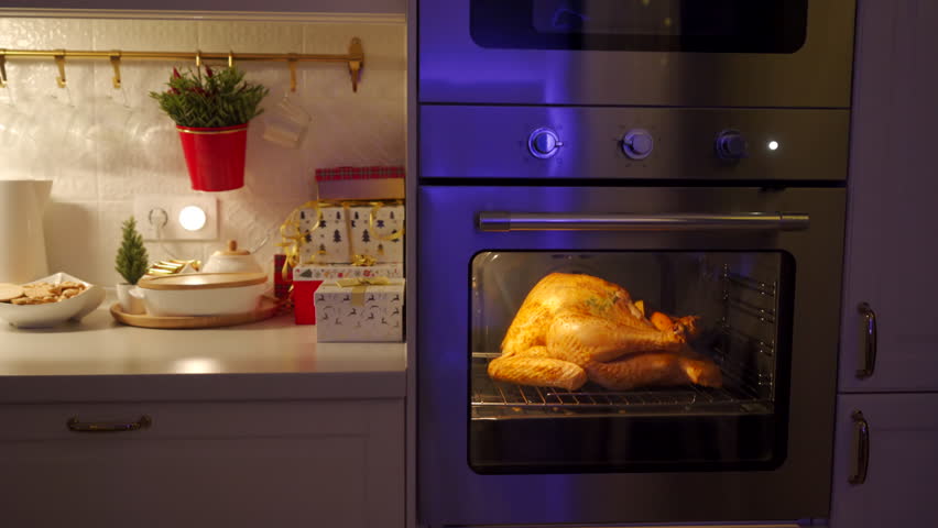 cooking roasted stuffed turkey in kitchen oven, thanksgiving and christmas holiday dinner