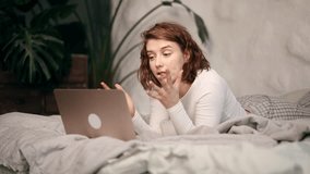 Irritated arguing young woman yelling at laptop computer while laying on bed at home Angry nervous female talk by video call expressing negative emotion Bad conflict working or personal conversation