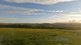 Scenic train ride through rolling hills of Scottish countryside at golden sunset. View from the window of a travelling train passing endless green fields, grazing animals and idyllic small villages. - Powered by Shutterstock - Get 15% off with code: PIKWIZARD15