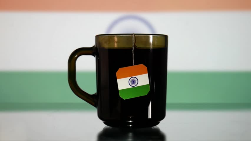 A black glass cup of tea with an India flag tag and a man's hand takes it Royalty-Free Stock Footage #3409655669