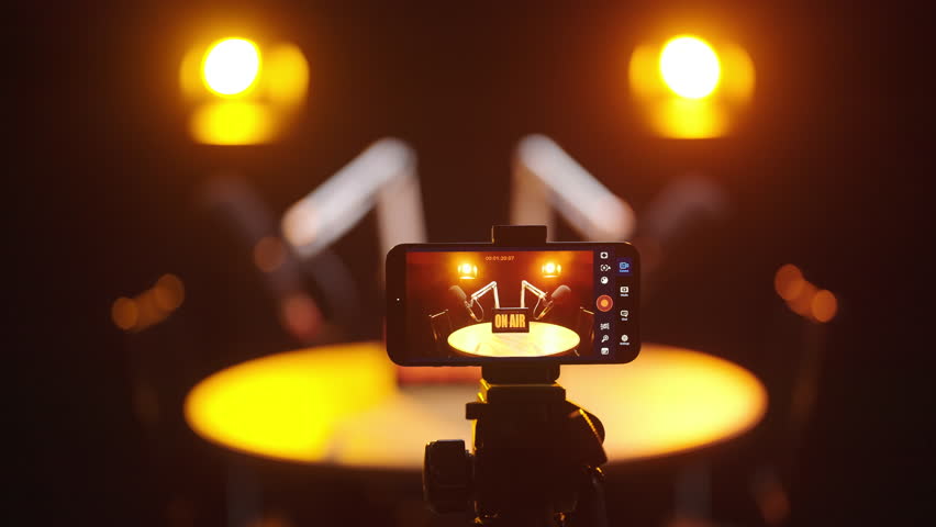 Sliding over smartphone recording video podcast in black studio with spotlights