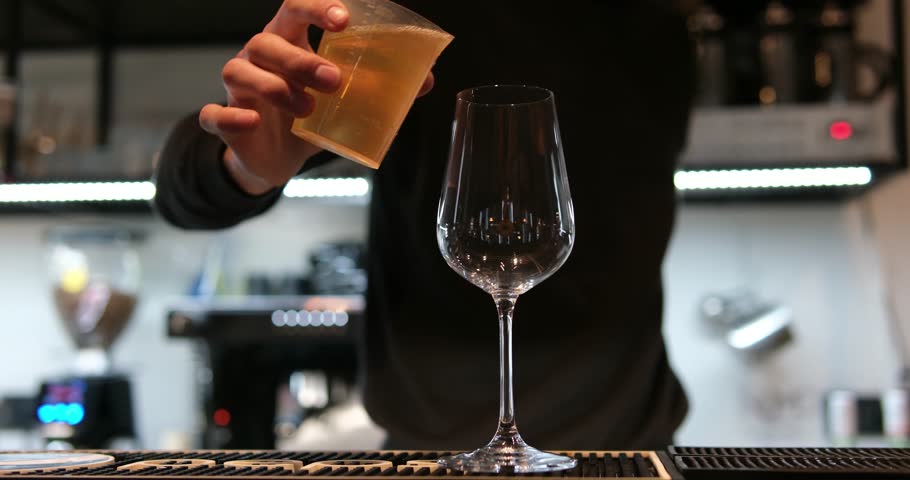 Pouring White Wine in Glasses at the bar counter A man in a white shirt holds a glass of wine