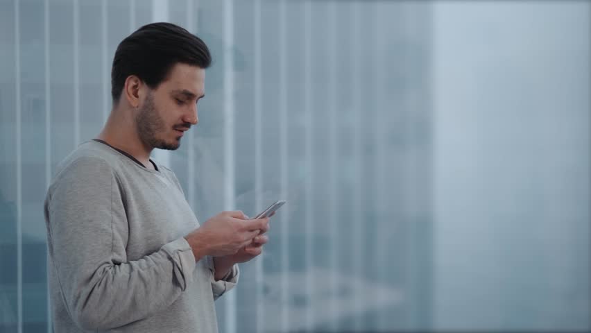 Portrait of young businessman talk on cellphone while stand by his office window in modern interior of skyscraper building, male entrepreneur having mobile phone conversation after important briefing Royalty-Free Stock Footage #34096843