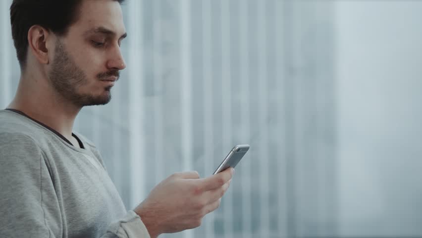 Portrait of young businessman talk on cellphone while stand by his office window in modern interior of skyscraper building, male entrepreneur having mobile phone conversation after important briefing Royalty-Free Stock Footage #34096852