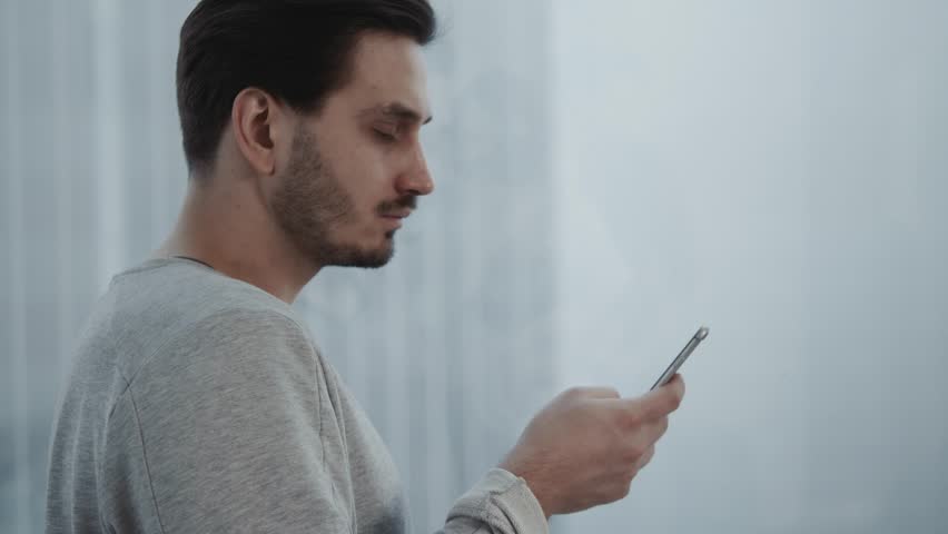 Portrait of young businessman talk on cellphone while stand by his office window in modern interior of skyscraper building, male entrepreneur having mobile phone conversation after important briefing Royalty-Free Stock Footage #34096855