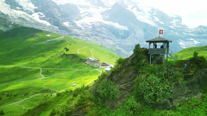 Drone Switzerland 4k. Swiss flag, hikers in Swiss Alps. Train station Kleine Scheidegg. Tourist destination near Jungfraujoch, Grindelwald. Swiss Alps in summer. Royalty-Free Stock Footage #3409692033