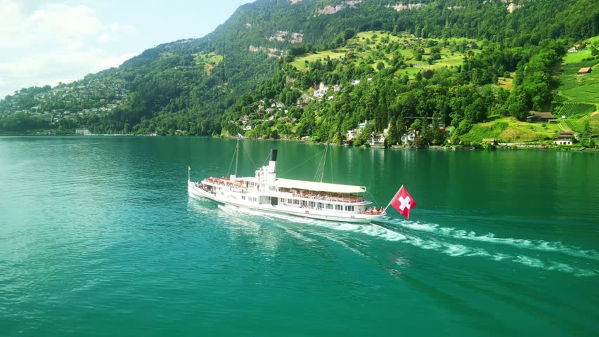 Aerial drone view of steamboat ship in Lake Lucerne. Swiss Flag. Beautiful Swiss Alps nature in summer Switzerland, 4k. Turquoise blue lake water. 