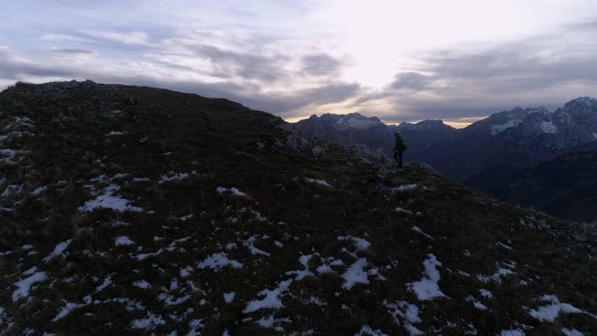 Aerial - Flyover young woman arriving to the top of the mountain in Julian Alps at sunset