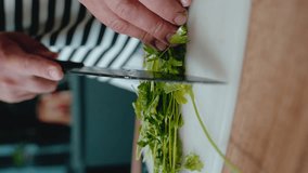 
Close-up of hands chopping parsley on a white board, ideal for stock videos on fresh herb preparation, cooking, and healthy food tutorials with a visually striking striped background.