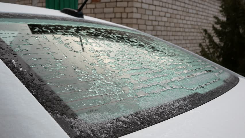 The rear window of the car freezes in the ice and thaws. the glass heats and melts