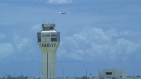 Daytime shot of a control tower at airport with plane passing by in slow motion
