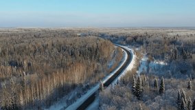 Aerial video view of winter road in taiga on Salair Ridge in winter. Abies sibirica trees covered by hoarfrost rise above the aspen forest in Siberia.