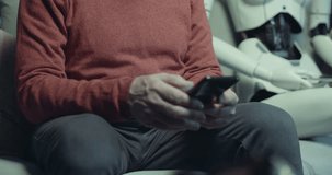 Senior man sitting on the couch at home with his android AI robot, he is using his smartphone and the robot is looking at him - Powered by Shutterstock - Get 15% off with code: PIKWIZARD15