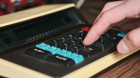 Counting on a vintage calculator. Male hand press buttons on an old retro calculating machine close-up on a wooden desk. Concept counts home finances, currency, savings, financial bills. - Powered by Shutterstock - Get 15% off with code: PIKWIZARD15