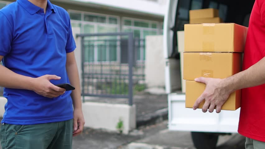 Man uses mobile phone to confirm payment before picking up parcel from deliveryman. Customer handwriting on phone to pick up package from postman.