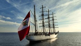 Aerial drone video of beautiful three mast barque or barc type classic sailing wooden boat with huge waving flag anchored in Mediterranean deep blue Aegean sea at sunset with golden colours - Powered by Shutterstock - Get 15% off with code: PIKWIZARD15