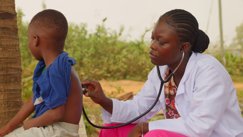 Africa healthcare: black female doctor listening the lungs of a young children using stethoscope in open air clinic hospital 