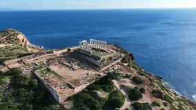 Aerial drone video of iconic archaeological site of Cape Sounio and famous Temple of Poseidon built uphill overlooking Aegean sea, Attica, Greece