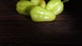 Ripe, juicy bell peppers, decorated with drops of water, lie on a rustic wooden table against a dark background. Suitable for content about healthy food, organic products and farm food.